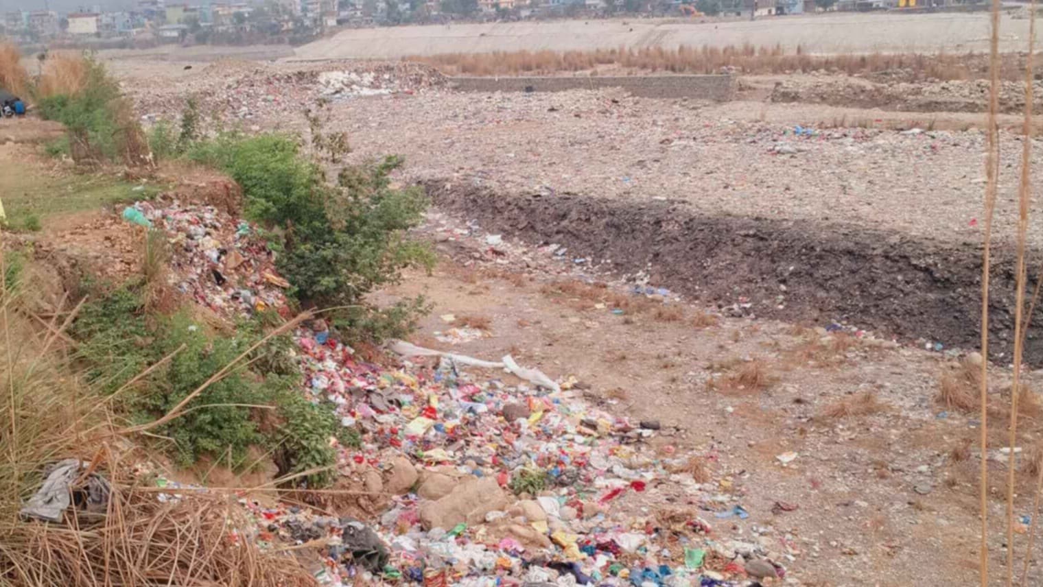 Image of a dumping site at Butwal- 11, Majhuwa that is situated on the Tinahu Riverbed near the residential area. The waste is separated from the river water by a side wall.